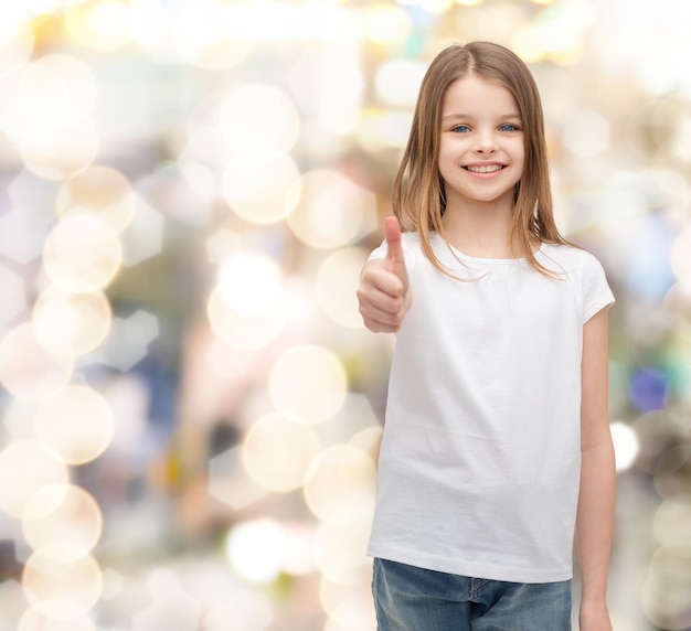 design de t-shirt et concept de personnes heureuses - petite fille souriante en t-shirt blanc vierge montrant les pouces vers le haut