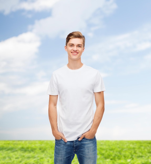 design de t-shirt, été, publicité et concept de personnes - jeune homme souriant en t-shirt blanc vierge sur fond naturel