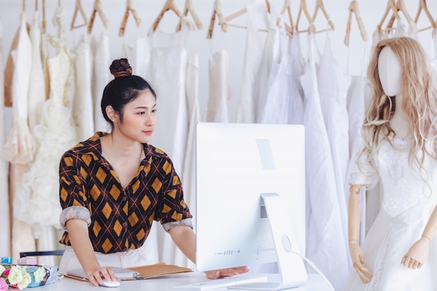 Designer asiatique travaillant dans un magasin de mode de mariage