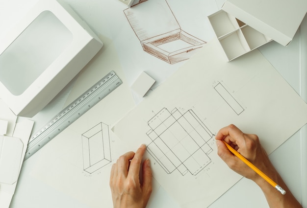 Le designer dessine un croquis pour un emballage en carton. Créez des boîtes de papier écologiques.