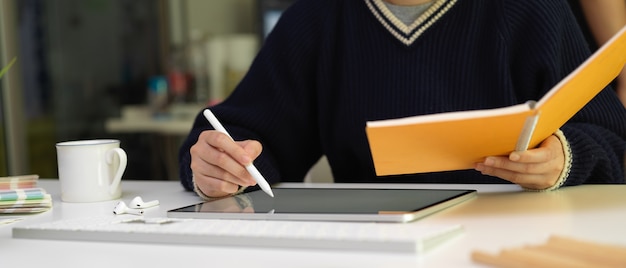 Designer féminin s'appuyant sur une tablette numérique avec stylet et à la recherche d'informations sur le calendrier