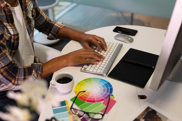 Photo designer graphique masculin travaillant à l'ordinateur à son bureau au bureau