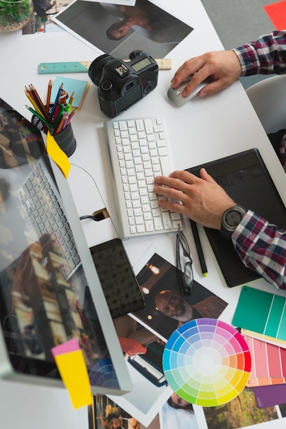 Photo designer graphique travaillant sur ordinateur à son bureau dans un bureau