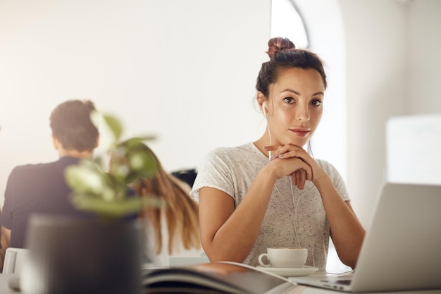 Designer indépendant travaillant sur un ordinateur portable buvant du café dans un espace de coworking ou un café écoutant de la musique en streaming en ligne dans des écouteurs ou un étudiant étudiant la mode ou les disciplines graphiques