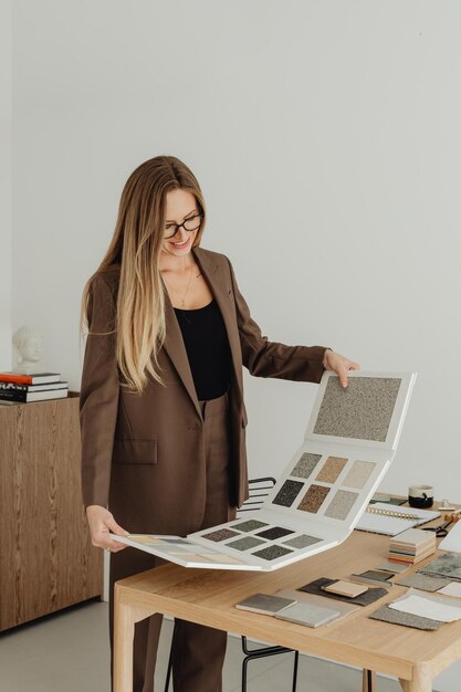 designer d'intérieur féminin travaillant à son bureau à la recherche de catalogues de couleurs de tissu
