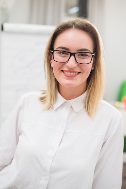 Designer jolie blonde souriant à la caméra dans le bureau créatif