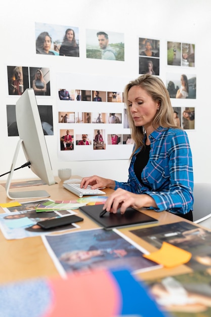 Photo designer de mode féminine utilisant une tablette graphique à son bureau