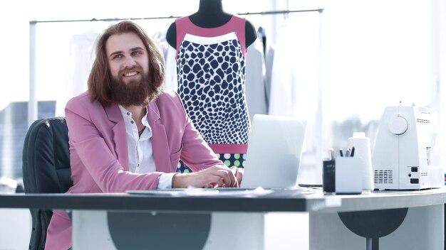 Un designer à succès travaille sur un ordinateur portable assis dans son studio