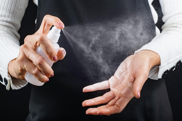 Désinfection des mains avec un spray désinfectant antimicrobien sur fond noir