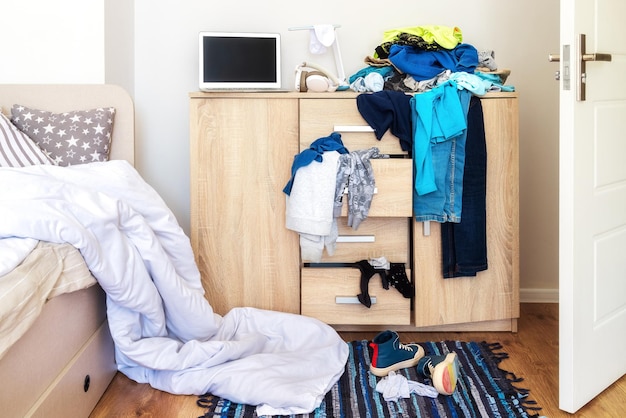 Désordre dans la chambre d'un adolescent Des vêtements sont éparpillés sur le sol de la commode