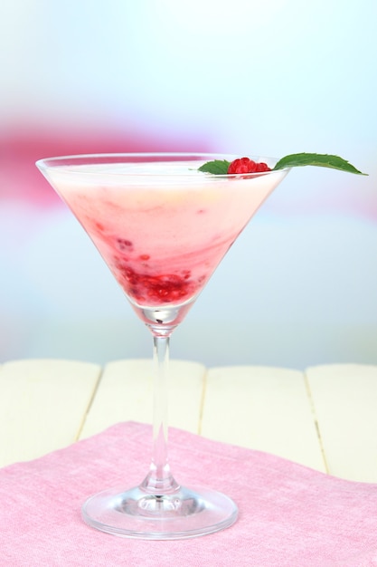 Dessert au lait de framboise en verre à cocktail, sur fond clair