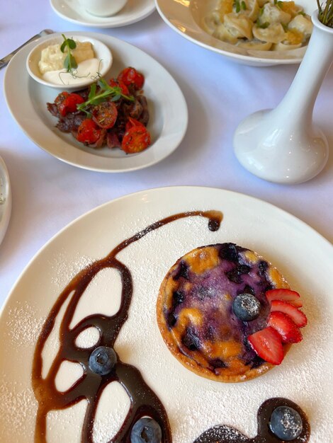 Photo un dessert aux baies dans une grande assiette légère devant d'autres plats dans un restaurant.