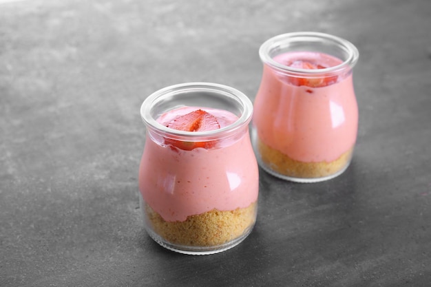 Dessert aux fraises fait maison avec du yaourt dans des bocaux en verre sur fond gris