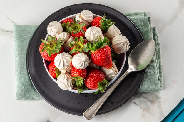 Dessert aux fraises avec meringue dulce de leche servi dans un bol sur fond de marbre