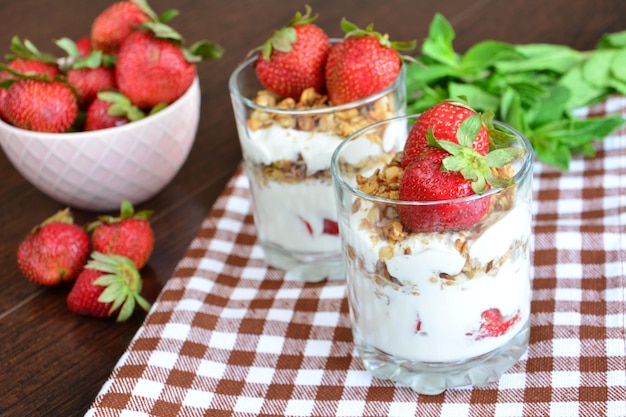 dessert aux fraises avec yaourt, granola et feuilles de menthe sur le fond en bois