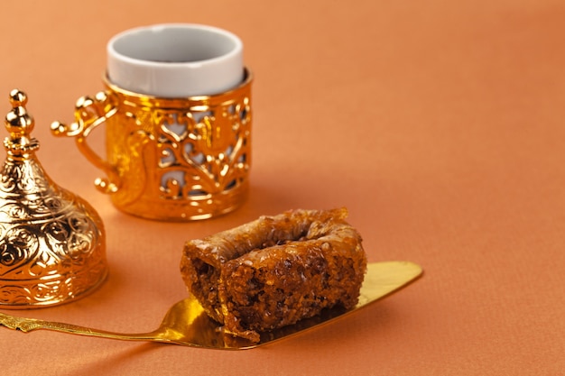 Dessert Baklava sur spatule dorée et tasse à café sur fond beige