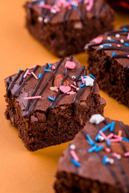 Dessert brownie au chocolat avec noix d'amande, glaçage au chocolat sur une surface orange