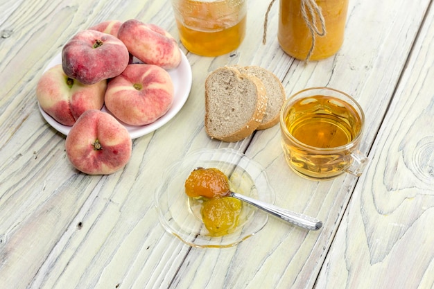 Dessert Confiture de pêches et thé et pain gros plan sur une table en bois