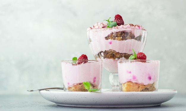 Dessert en couches rose, tiramisu ou parfait aux framboises et à la menthe décoré de poudre de cacao dans des verres