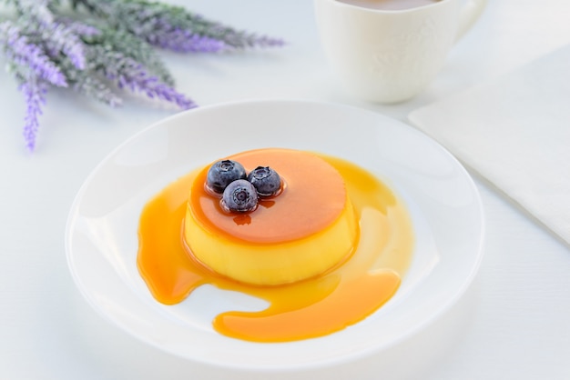 Dessert à la crème au caramel avec des bleuets, de la lavande et une tasse de café