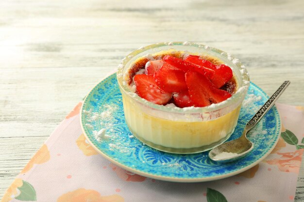 Dessert crème brûlée avec des baies de fraises fraîches sur une serviette sur fond de bois de couleur