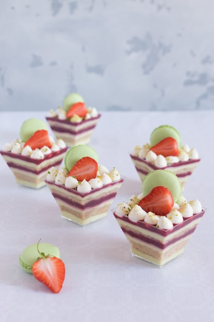 Dessert dans des tasses avec des fraises fraîches et des macarons sur un tableau blanc