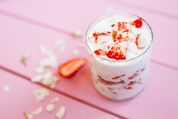 dessert d'été en couches avec des fraises, du gâteau éponge et du yaourt sur un fond d'arbre rose.