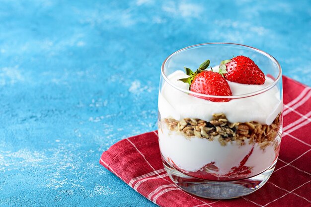 Dessert à la fraise avec mousse de fromage cottage, granola en verre sur serviette bourgogne