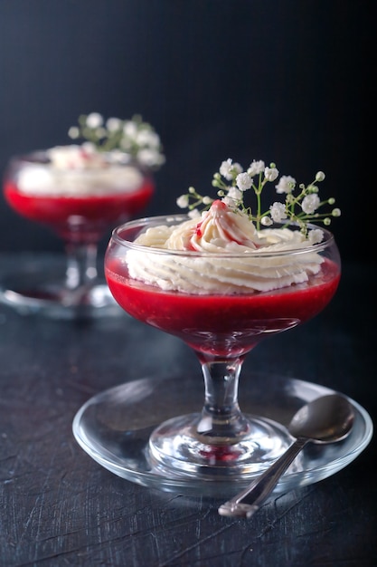 Dessert framboise-fraise avec crème au fromage en verrin sur une surface noire