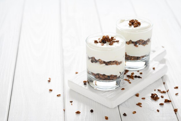 Dessert avec fromage mascarpone et granola sur fond de bois blanc