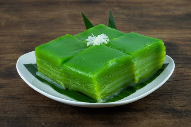 Dessert de gâteau de couche de pandan vert cuit à la vapeur typique de la Thaïlande sur une plaque blanche sur fond de bois