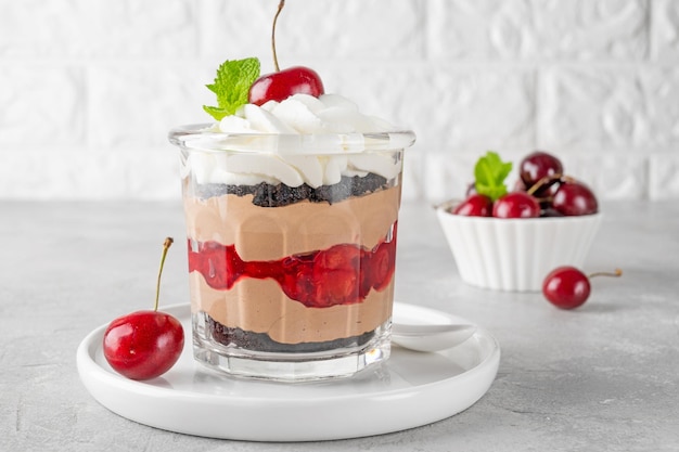 Dessert gâteau forêt noire dans un verre Bagatelle au chocolat avec biscuit à la crème au chocolat et cerise