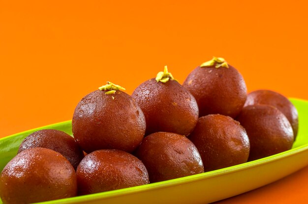 Dessert indien Gulab Jamun dans une assiette sur fond orange