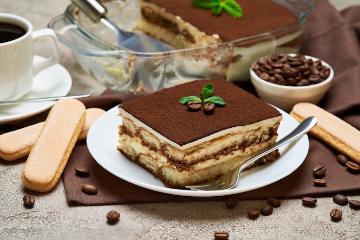 Photo dessert italien traditionnel au tiramisu dans un plat de cuisson en verre et une portion sur une table en béton gris