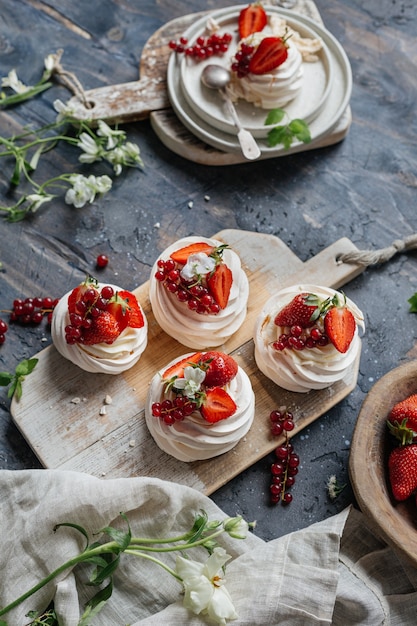 Photo dessert meringue aux baies servi sur une planche en bois.