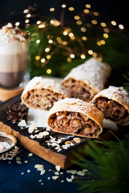 Dessert de Noël fait maison, strudel aux pommes, gâteau sur la table de fête avec guirlandes, mise au point sélective