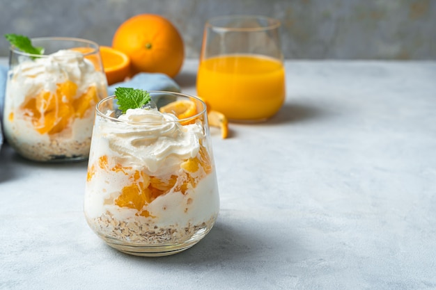 Dessert orange à la crème et à la menthe sur un bureau gris. Crème fouettée et fruits.