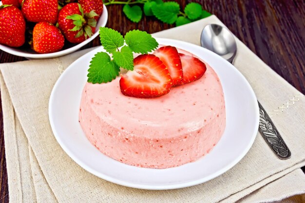 Dessert panna cotta de lait caillé et menthe fraise et baies dans le bol sur une serviette beige sur fond de planches de bois