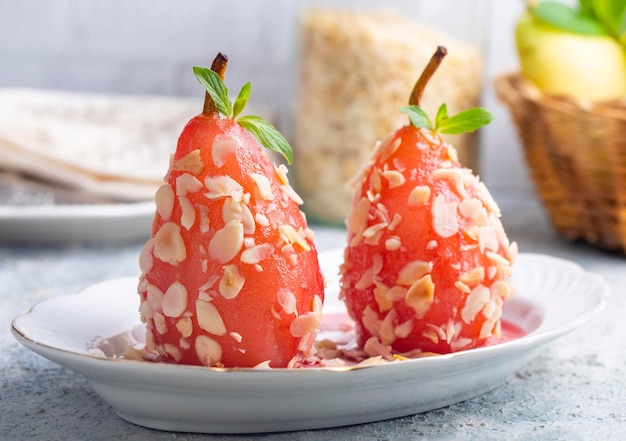 Un dessert de poire pochée saupoudré de morceaux d'amande Un goût de desserts turcs dessert de paire Poire pochée dans du vin rouge