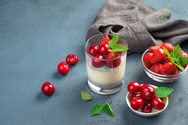 Dessert sain et délicieux avec des graines de chia et des cerises et des fraises fraîches, du pudding au lait. La nourriture saine. Vue latérale, copiez l'espace.