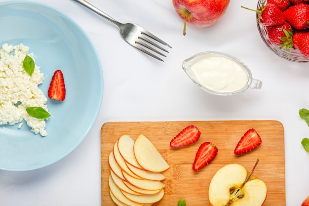 Dessert sain avec du fromage cottage et des fraises en plaque bleue sur une nappe blanche