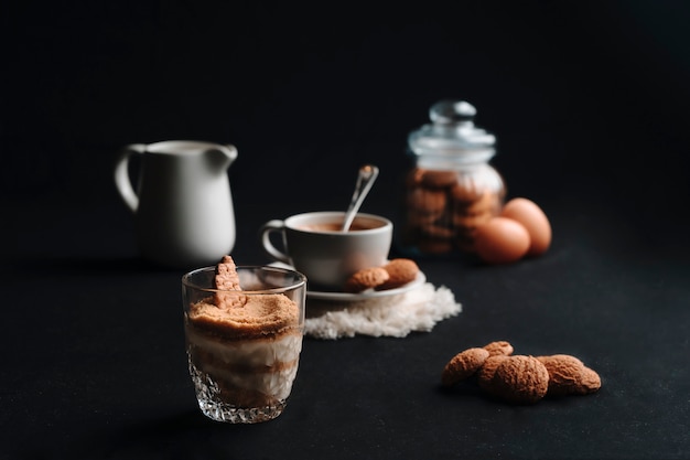 Dessert Serradura et café chaud avec quelques biscuits et un fond sombre