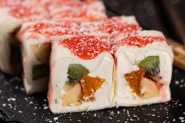 Dessert sucré asiatique maki sushi closeup roll avec fruits et fromage à la crème avec des flocons de noix de coco et top