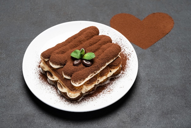 Dessert tiramisu classique sur assiette en céramique et poudre de cacao en forme de coeur