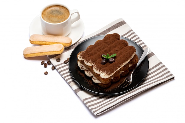 Dessert tiramisu classique sur plaque en céramique, biscuits savoiardi et tasse de café isolé sur une surface blanche avec un tracé de détourage