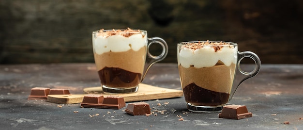 Dessert avec trois couches de mousse de chocolats crème brûlée au chocolat vanille dessert sur fond sombre format bannière longue