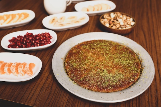 Dessert turc kunefe kunafa kadayif avec de la poudre de pistache et du fromage chaud mangé un bonbon