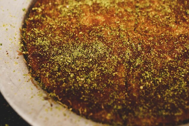 Dessert turc kunefe kunafa kadayif avec de la poudre de pistache et du fromage chaud mangé un bonbon