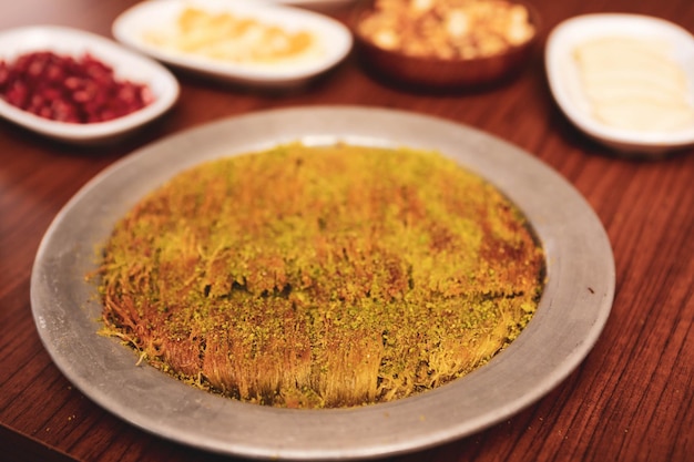 Dessert turc kunefe kunafa kadayif avec de la poudre de pistache et du fromage chaud mangé un bonbon