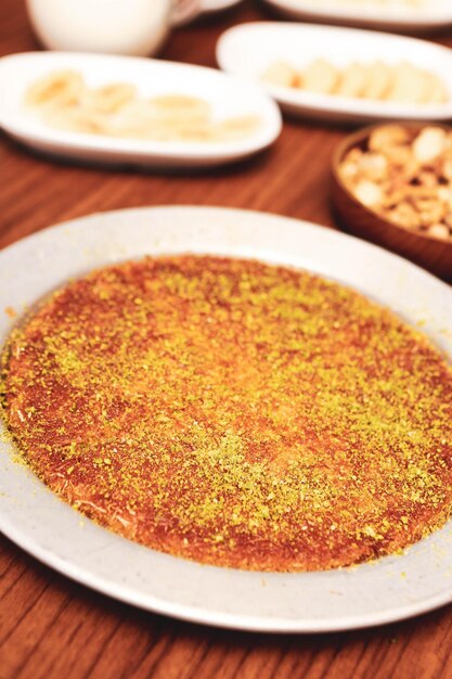 Dessert turc kunefe kunafa kadayif avec de la poudre de pistache et du fromage chaud mangé un bonbon